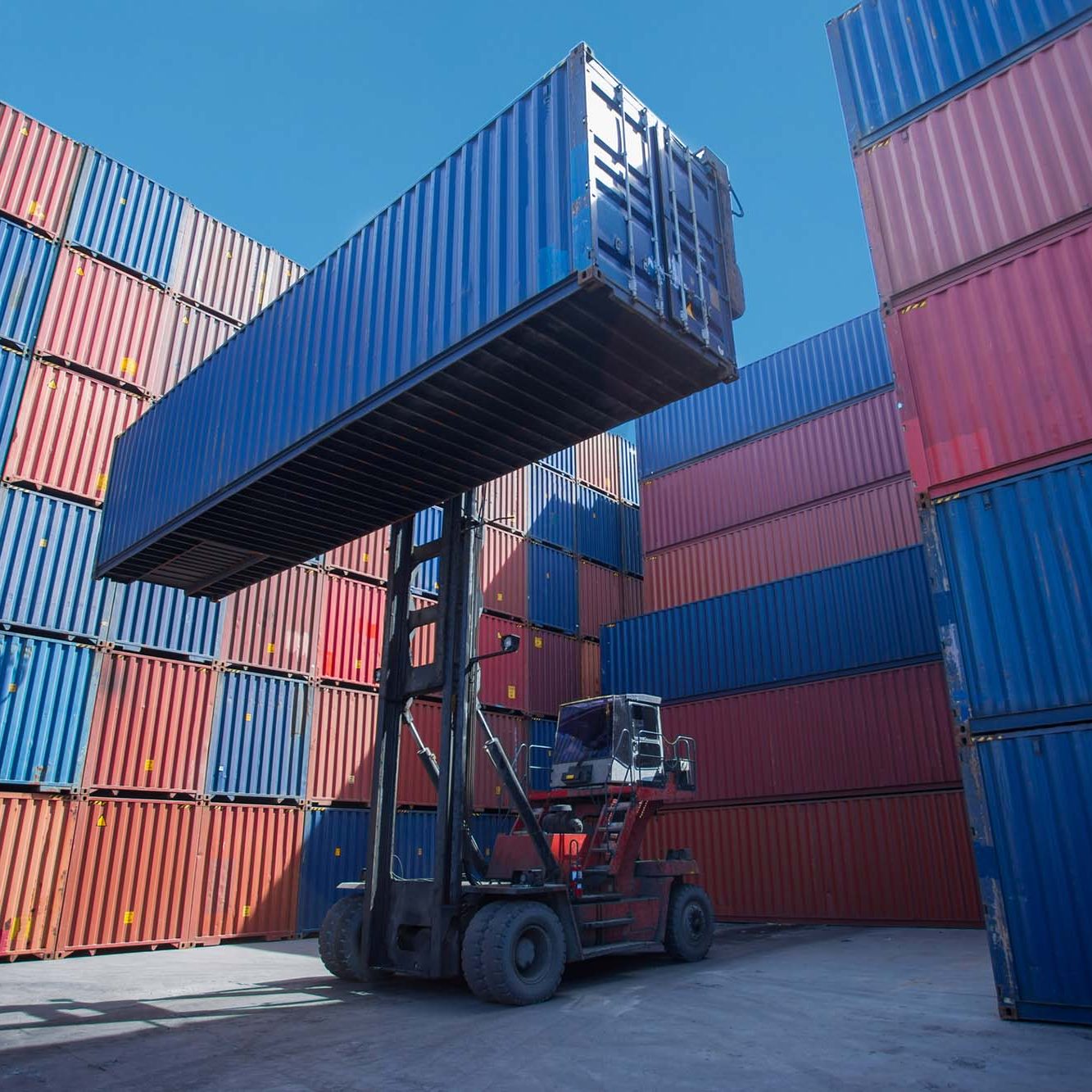Forklift truck lifting cargo container in shipping yard or dock